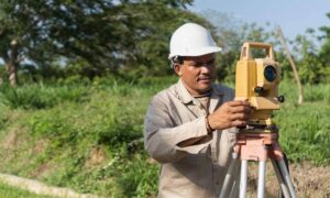 Land surveyor using a total station to perform field measurements during the land survey process