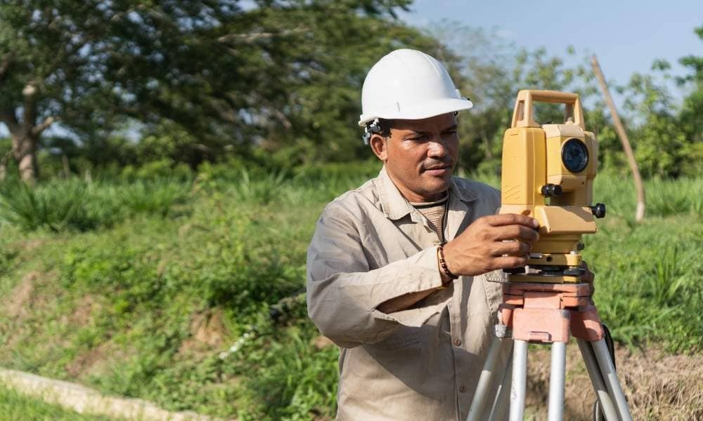 Land surveyor using a total station to perform field measurements during the land survey process